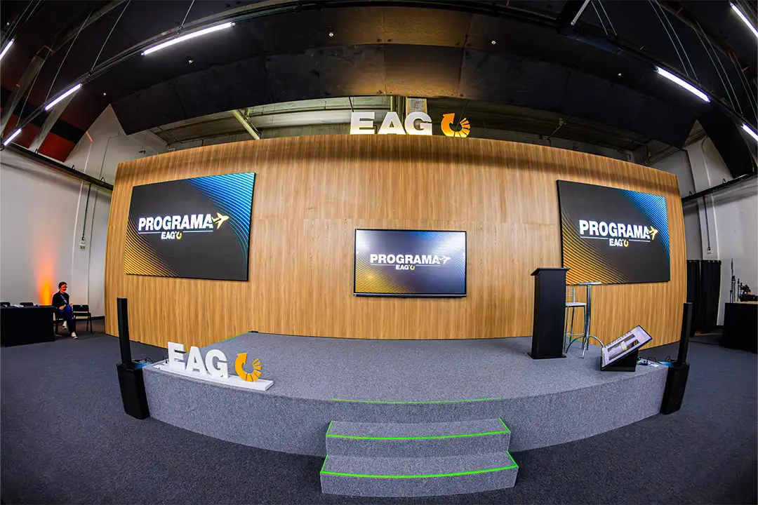 Palco profissional do Centro de Eventos EAG com painel de madeira e telões 4K para eventos corporativos
